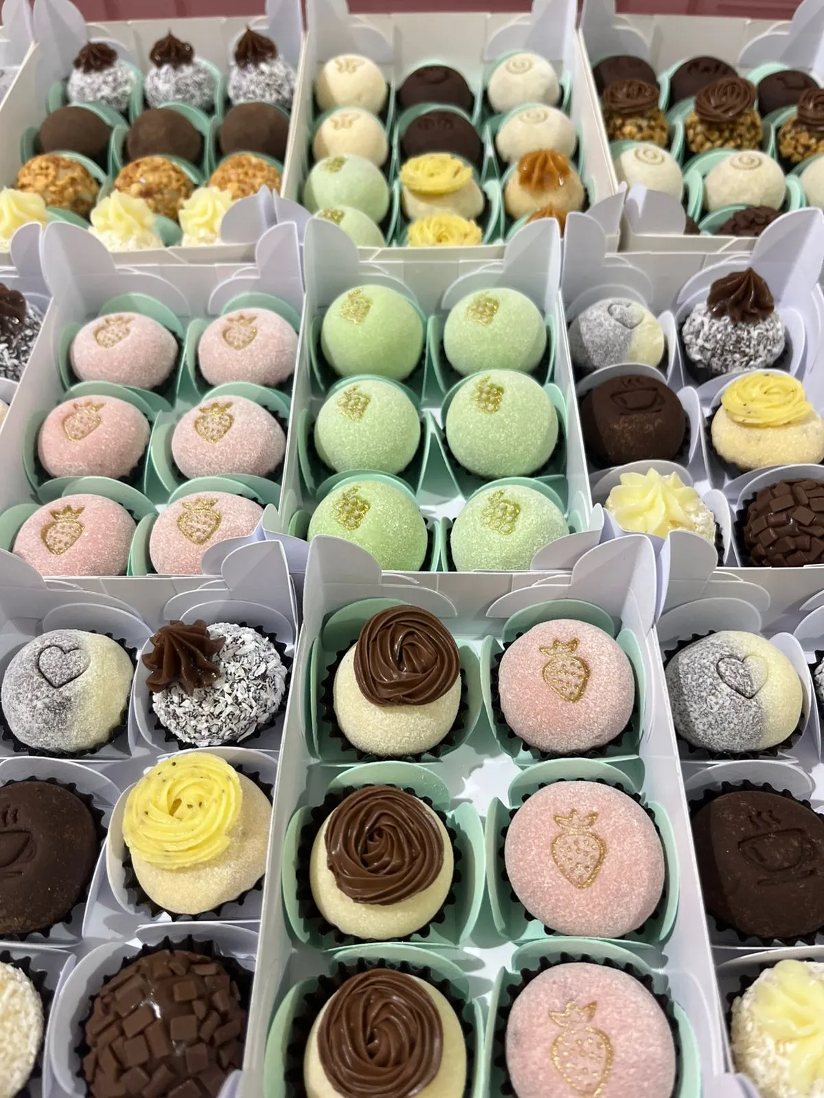 Seleção de caixas com brigadeiros sortidos em tons pastel.