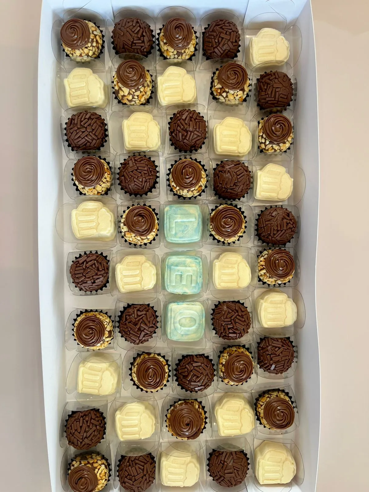 Caixas com brigadeiros sortidos em tons delicados.